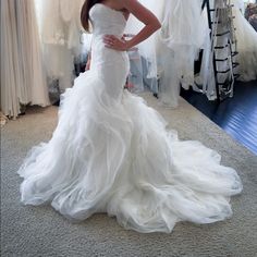 a woman standing in front of a mirror wearing a wedding dress with ruffles on it