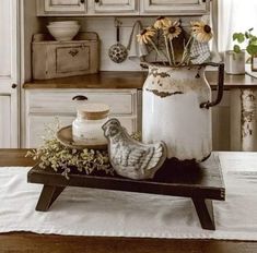 an old milk can with flowers in it sitting on a table next to a bird