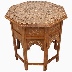 an octagonal wooden table with intricate carvings on the top and bottom, sitting against a white background