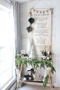 a bar cart with bottles of wine on it in front of a window