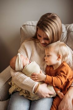 a woman sitting on a couch holding a baby