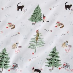 a white fabric with cats and dogs in the woods on snowflakes, trees, and sleds