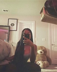 a woman taking a selfie with her cell phone in front of a teddy bear