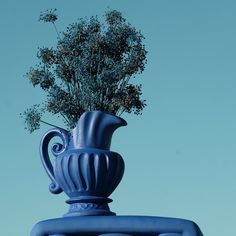 a blue vase with flowers in it on top of a building roof against a blue sky