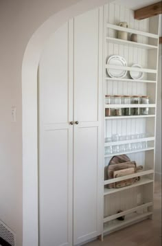 an arched doorway leads to a pantry with white cupboards