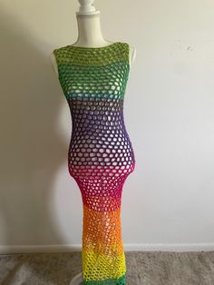 a mannequin is made out of multicolored knitted material and stands in front of a white wall