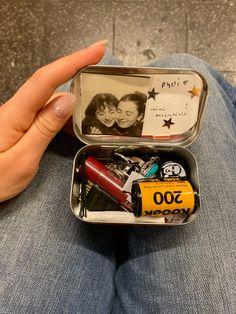 a person holding an open tin with personalized items in it