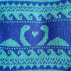 a blue and green knitted blanket with hearts on it