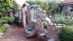 a brick building with an arched window in the center and flowers growing all around it