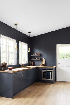 an empty kitchen with black walls and wooden flooring is seen in this image from the front view