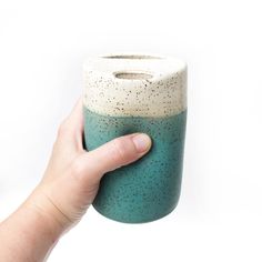 a hand holding a blue and white vase with sprinkles on it's side