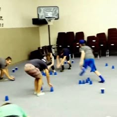 some people are doing tricks in an indoor basketball court with blue cones on the floor