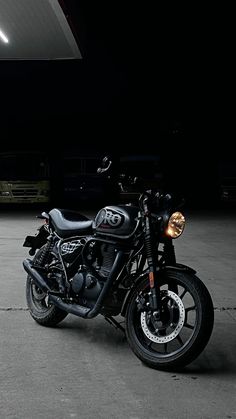 a black motorcycle parked in an empty parking lot at night with the lights turned on