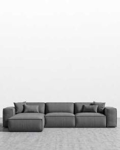 a large gray couch sitting on top of a wooden floor next to a white wall