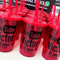 red plastic cups with straws are lined up on a table in front of black and white signs