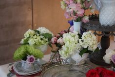 a table topped with plates and vases filled with flowers