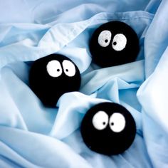 three black balls with googly eyes on a blue blanket