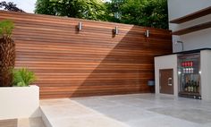 a modern house with wood slats on the wall and concrete flooring in front of it