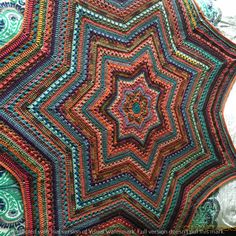 a multicolored crocheted blanket with an intricate star design on the top