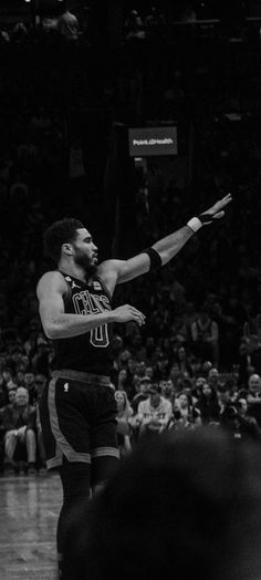 a black and white photo of a basketball player in the air with his arms out