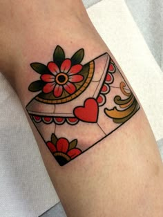 a woman's arm with a heart and flower tattoo design on the left forearm