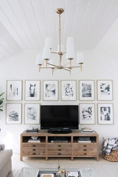 a living room with pictures on the wall and a television in the center, along with a coffee table