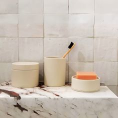 a marble counter top with two containers and a toothbrush holder sitting on it's side