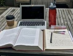 an open book sitting on top of a table next to a laptop computer and cup of coffee