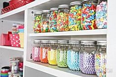 the shelves are filled with many different colored candies and other candy in glass jars