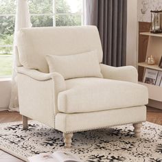 a white chair sitting on top of a rug in a living room next to a window