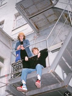 two people sitting on top of a metal structure