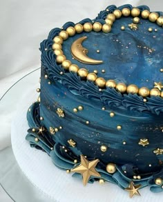 a blue cake with gold stars and moon decorations on it's side, sitting on a plate