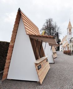 several wooden benches sitting on top of a brick road next to a building with a steeple