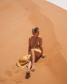 a woman sitting on top of a sandy dune