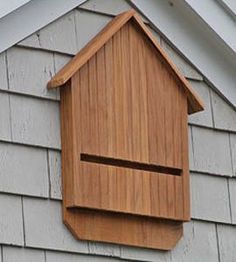 a wooden birdhouse hanging on the side of a house