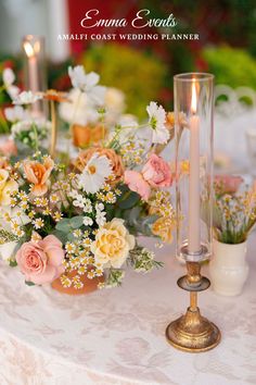 an arrangement of flowers and candles on a table