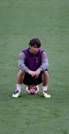 a man sitting on top of a soccer field with a ball in his hand,