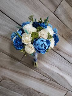 a bouquet of blue and white flowers on a wooden floor with wood planks in the background