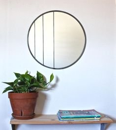 a potted plant sitting on top of a wooden table next to a round mirror