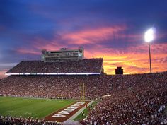 a football stadium filled with lots of people watching the sun go down on it's field