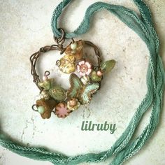 a necklace with flowers and leaves on it is hanging from a green cord that has the word lirrby written in front of it