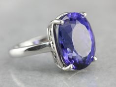 "One of the very finest gemstones currently in our collection, this Tanzanite is collectors quality, filled with color and shine. Weighing in at over ten carats, this incredible stone features a deep, true indigo color filled with flashed of cobalt and cornflower. We've set this tanzanite in a simple, substantial platinum mounting, one versatile enough to wear day or evening. Metal: Platinum Gem: Tanzanite, 10.20 Carats Gem Measures: 11 x14 mm, Oval Size: 5.25 Marks: \"PT950 J.L.J\" Stamped on t Cushion Cut Gemstones With Accent Stones For Formal Occasions, Formal Cushion Cut Gemstones With Accent Stones, Cushion Cut Gemstones For Formal Fine Jewelry, Cushion Cut Fine Jewelry Gemstones For Formal Occasions, Oval Gemstones With Prong Setting For Formal Occasions, Formal Cushion Cut Topaz Ring With Gemstone Accents, Cushion Cut Gemstones With Prong Setting For Formal Occasions, Exquisite Formal Gemstones With Accents, Oval Sapphire Gemstones For Formal Occasions