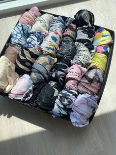 an open suitcase filled with lots of different types of scarves on top of a wooden floor