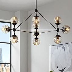 a modern chandelier hanging from the ceiling in a living room with large windows