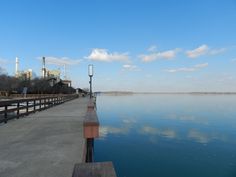 the water is calm and blue with clouds in the sky above it, as well as a light pole