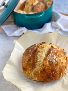 a loaf of bread sitting on top of a piece of paper next to a blue bowl