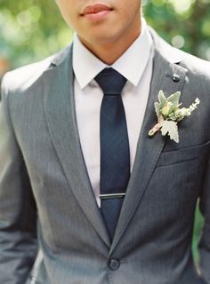 a man wearing a suit and tie with a boutonniere on his lapel