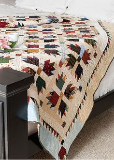 a bed with a quilt on top of it next to a night stand and nightstand