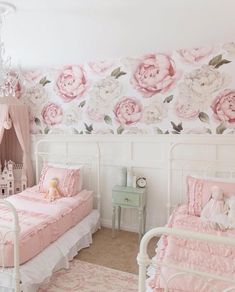 two beds in a room with pink flowers on the wall and a chandelier