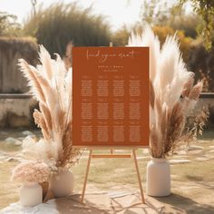 an orange and white wedding seating plan on a easel with pamodia in vases